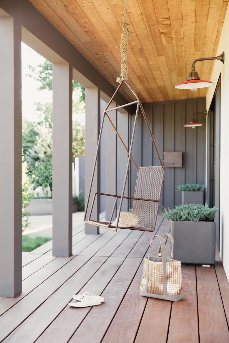 Fashionable A Modern Metal Swing Hangs From The Wood Plank Ceiling On Pertaining To Lamp Outdoor Porch Swings (View 8 of 30)